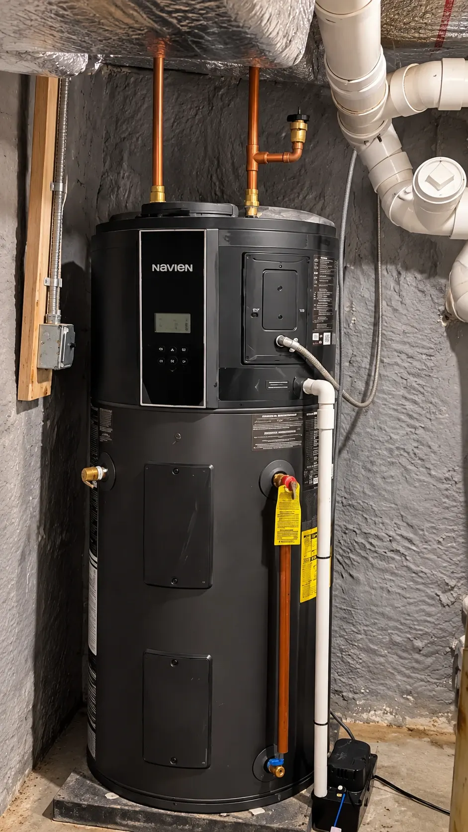 Navien heat pump water heater installed in a basement utility room, with surrounding plumbing, ductwork, and insulated piping visible.